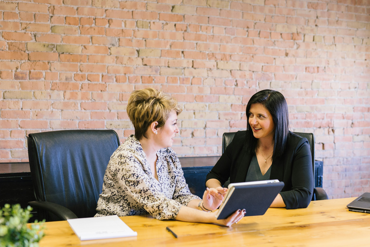 Two women discussing business on a desk in Birmingham. (Photo by Amy Hirschi on Unsplash)