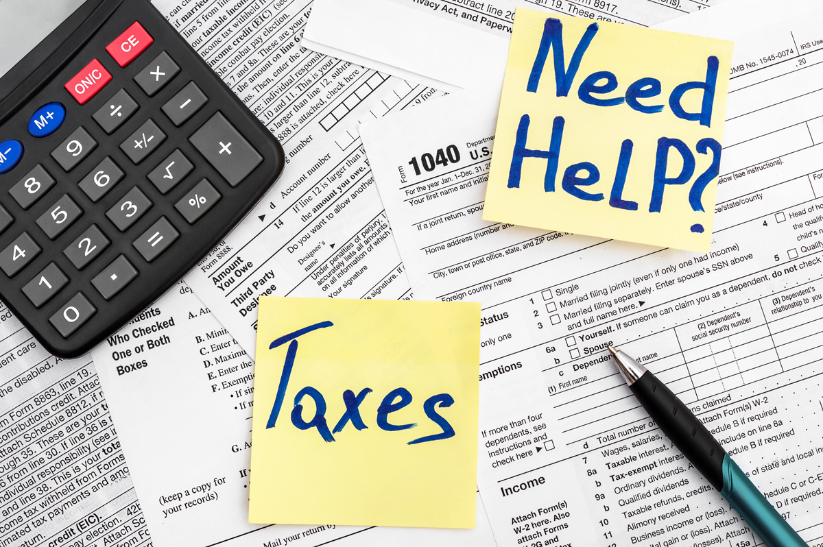 Tax forms with a calculator and two yellow sticky notes on top that read “Taxes” and “Need help?” in Birmingham.
